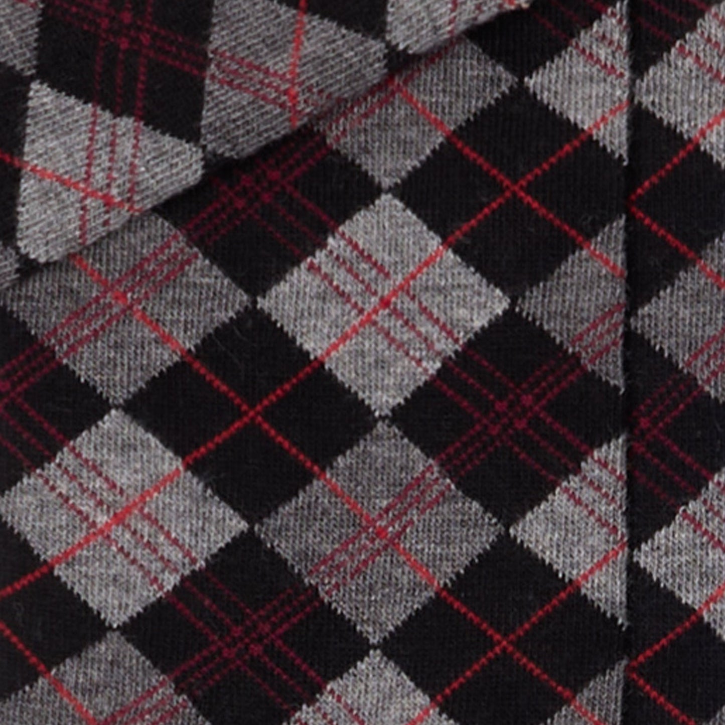 Dettaglio dei calzini scozzesi "Argyle" antracite lunghi da donna. di Arturo Stories. Con rombi grigi e neri, con filo rosso.