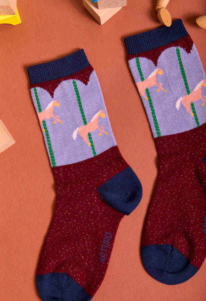 Calze da bambino di Arturo Stories. Con fantasia giostra, su fondo bordeaux, punta e tallone blu. Da zero a otto anni.