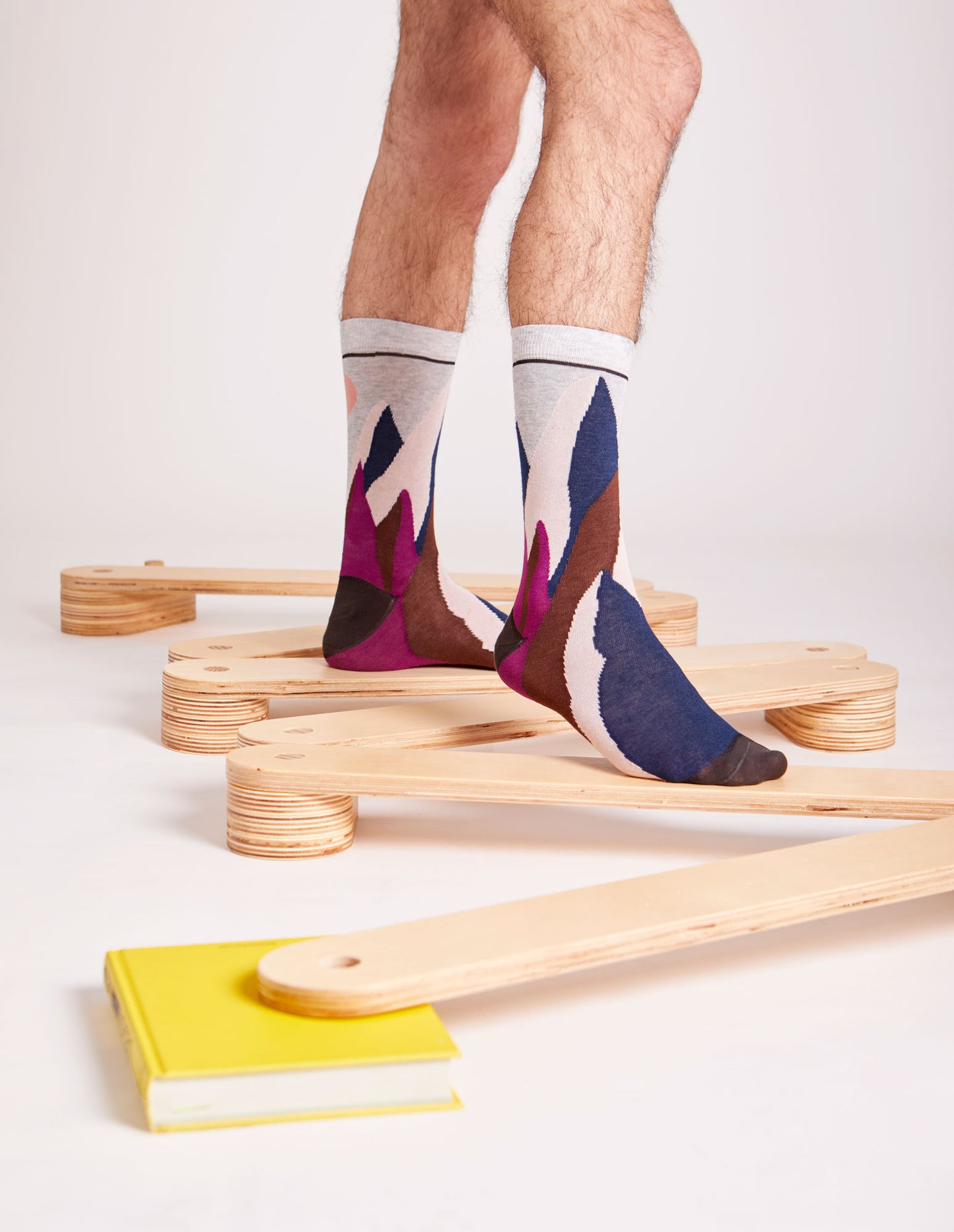 Calze "Svetta in alto" lunghi da uomo di Arturo Stories. Montagne e sole ricamati su fondo grigio chiaro.