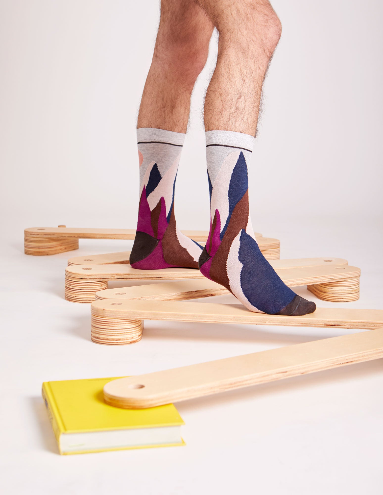 Calze "Svetta in alto" lunghi da uomo di Arturo Stories. Montagne e sole ricamati su fondo grigio chiaro.