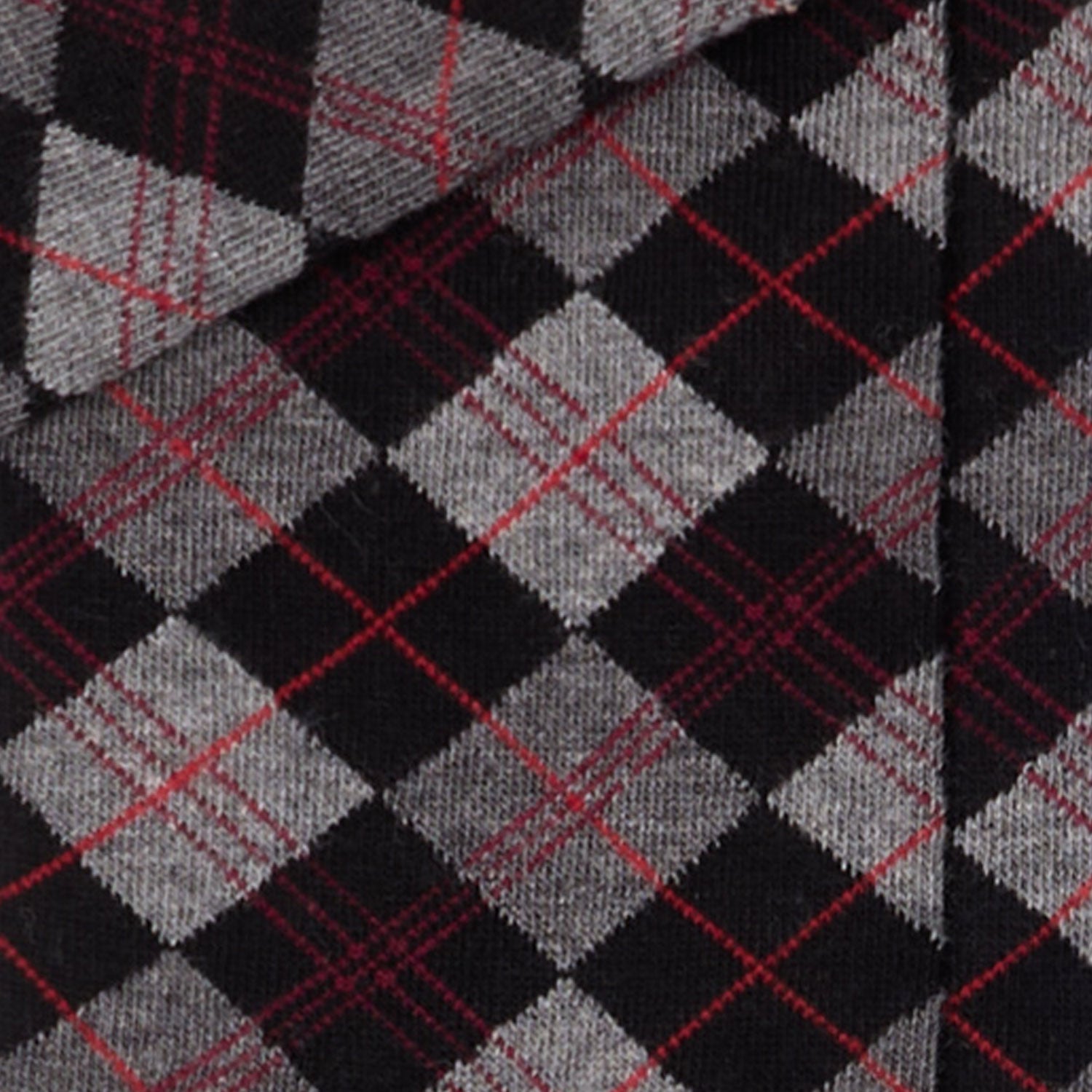 Dettaglio dei calzini scozzesi "Argyle" antracite lunghi da donna. di Arturo Stories. Con rombi grigi e neri, con filo rosso.