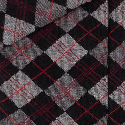 Dettaglio dei calzini scozzesi "Argyle" antracite lunghi da donna. di Arturo Stories. Con rombi grigi e neri, con filo rosso.
