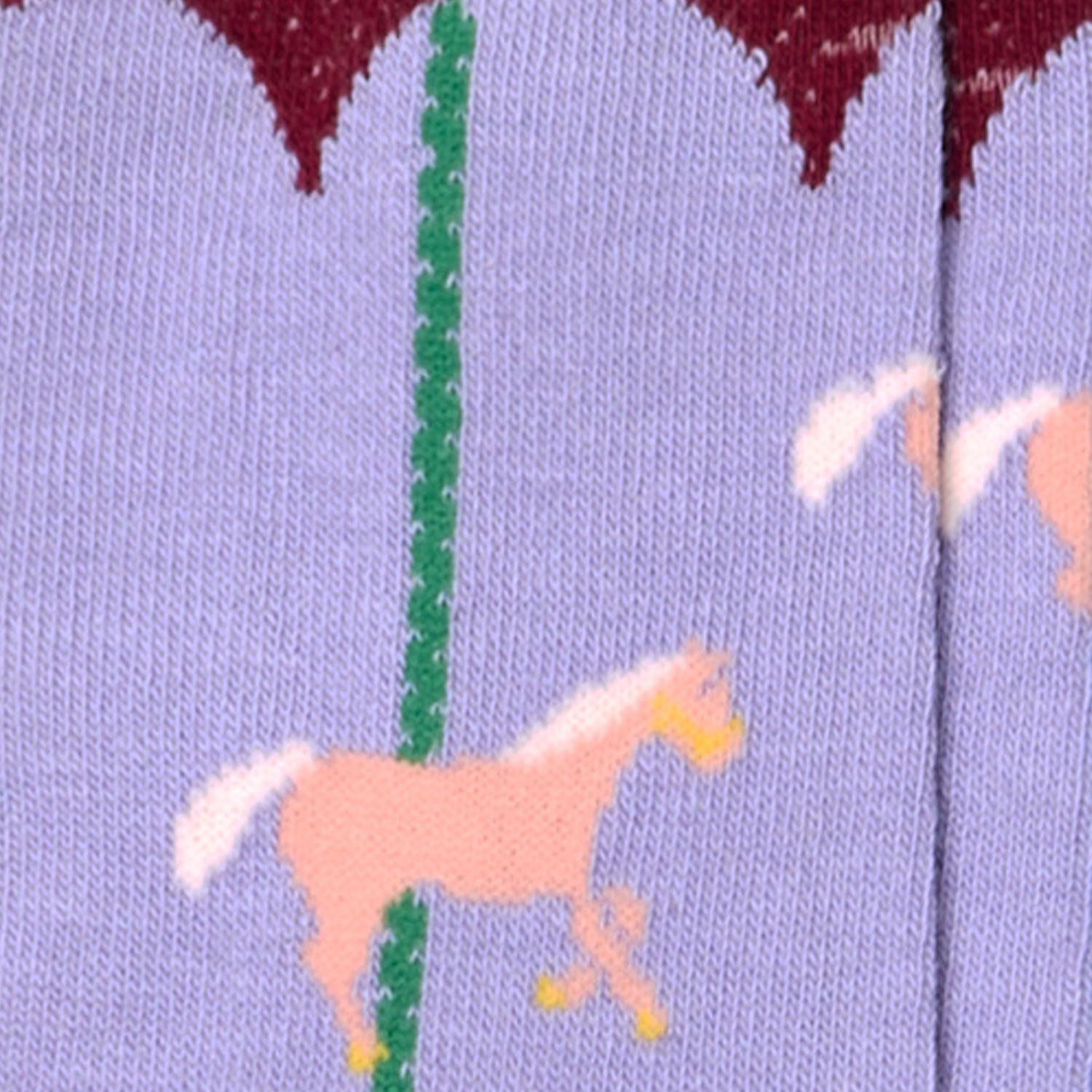 Dettaglio dei calzini da bambino di Arturo Stories. Con fantasia giostra, su fondo bordeaux, punta e tallone blu. Da zero a otto anni.