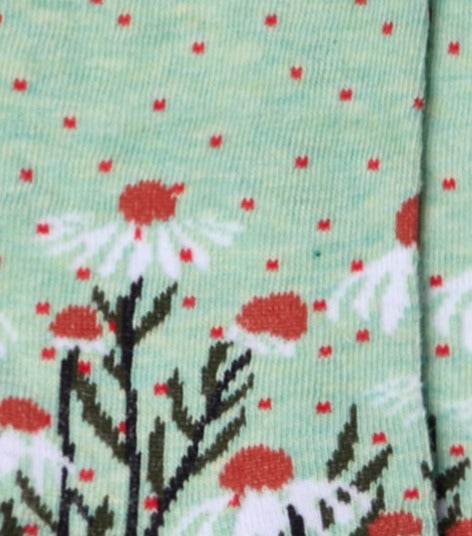 Dettaglio dei calzini con margherite verde menta da donna di Arturo Stories. Con fiori bianchi, punta e tallone neri e profilo nero lungo il retro della gamba.